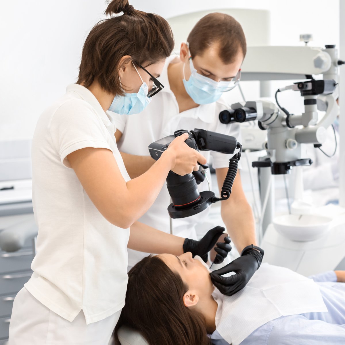 Two professional dentists taking photo of patient teeth in modern dental clinic, using camera